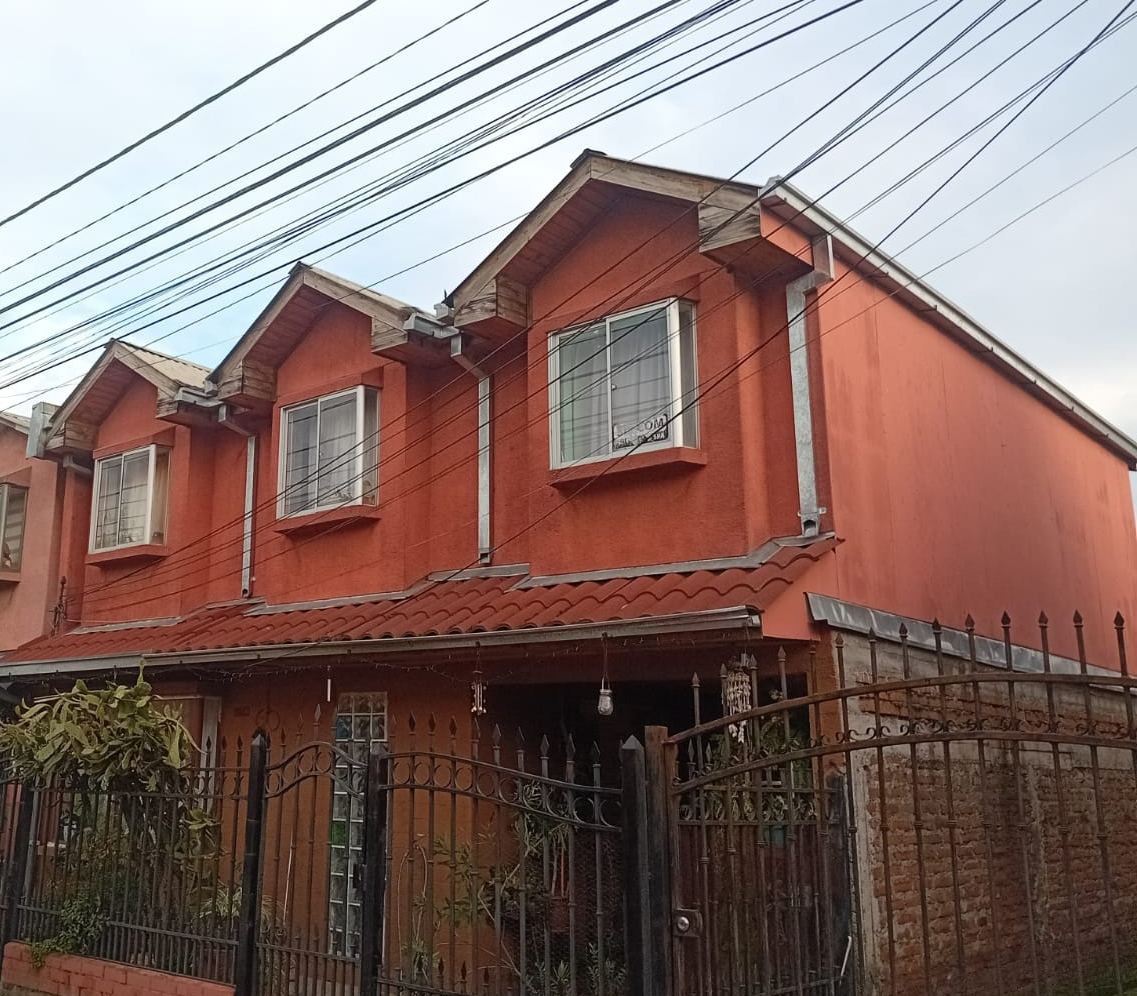 Casa de dos pisos con alero de teja, canaletas y bajadas