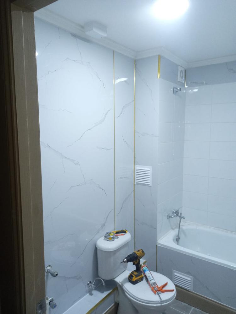 Baño con porcelanato símil mármol y guardacantos dorados